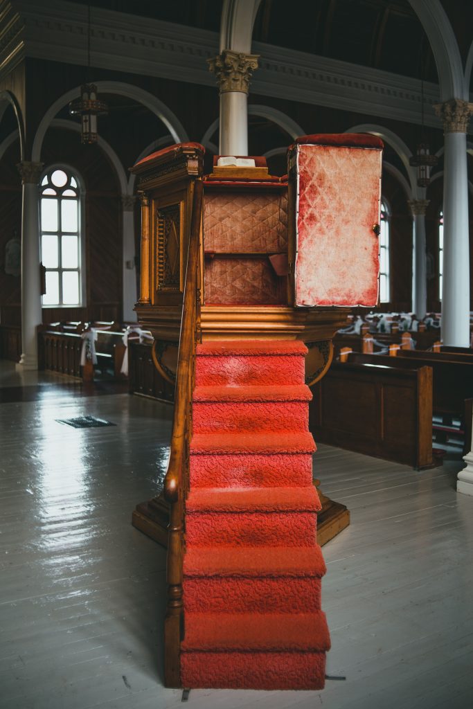 Elegant church pulpit with red carpeted stairs in a historical building, creating a serene atmosphere.