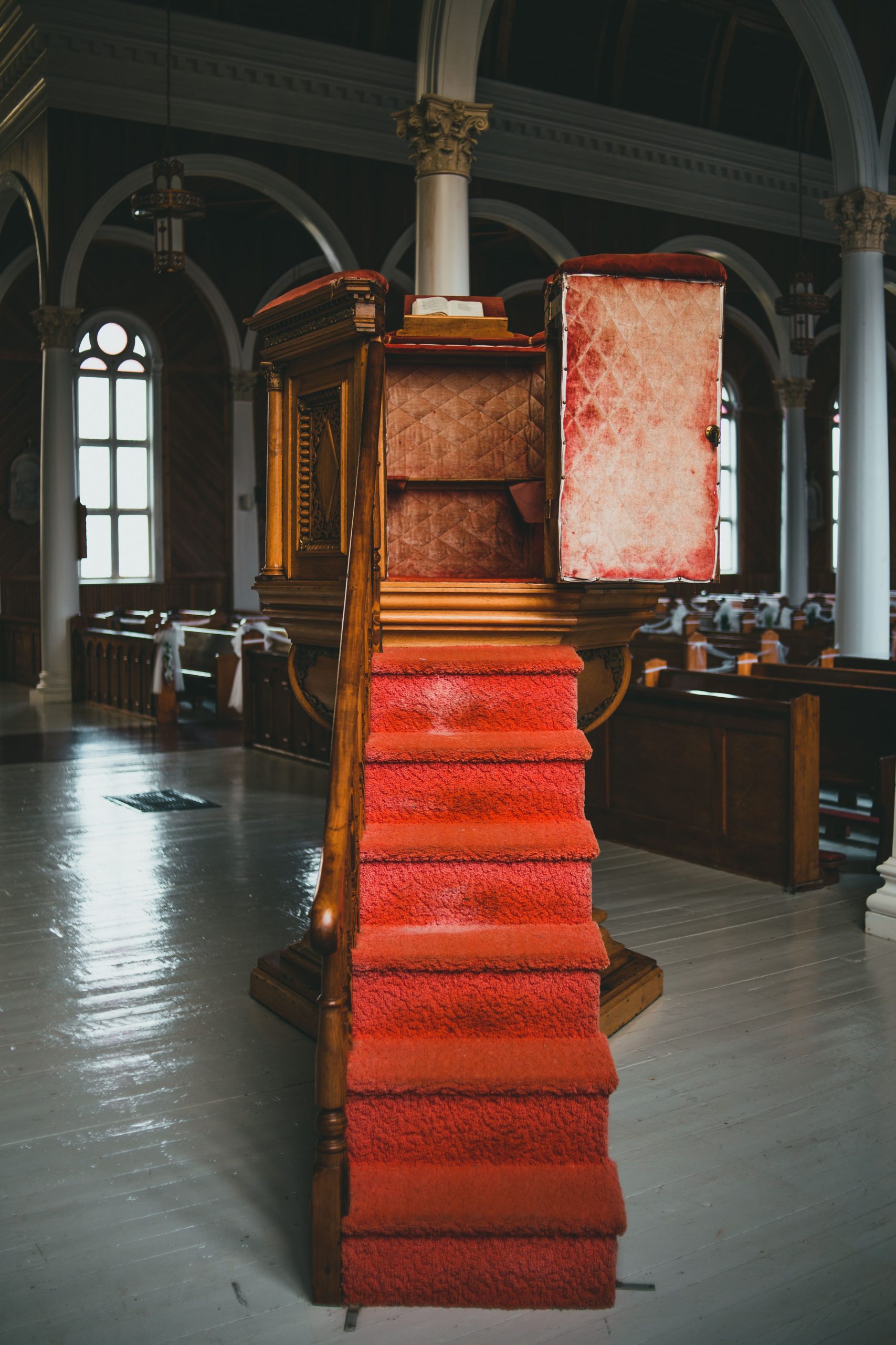 Elegant church pulpit with red carpeted stairs in a historical building, creating a serene atmosphere.